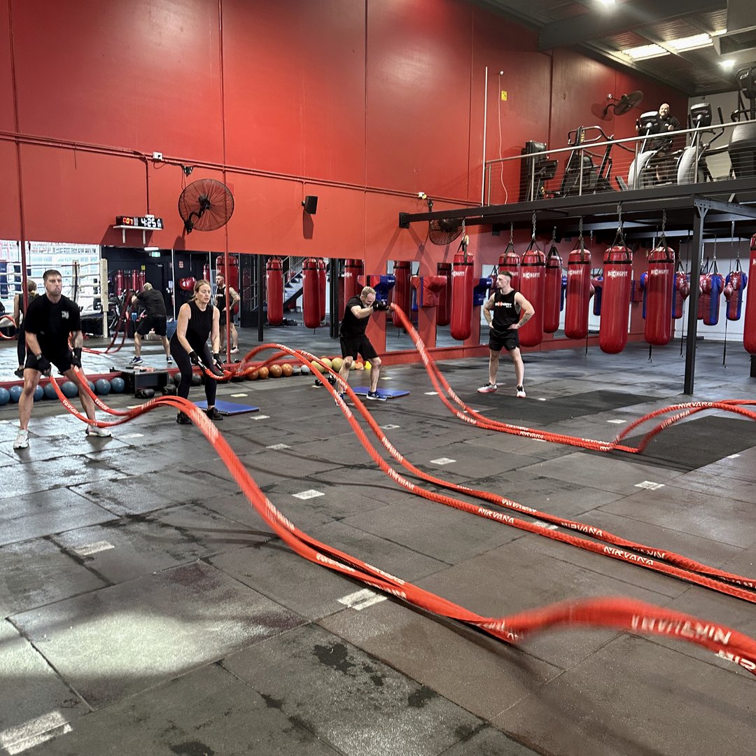Members training with battle ropes on the gym floor