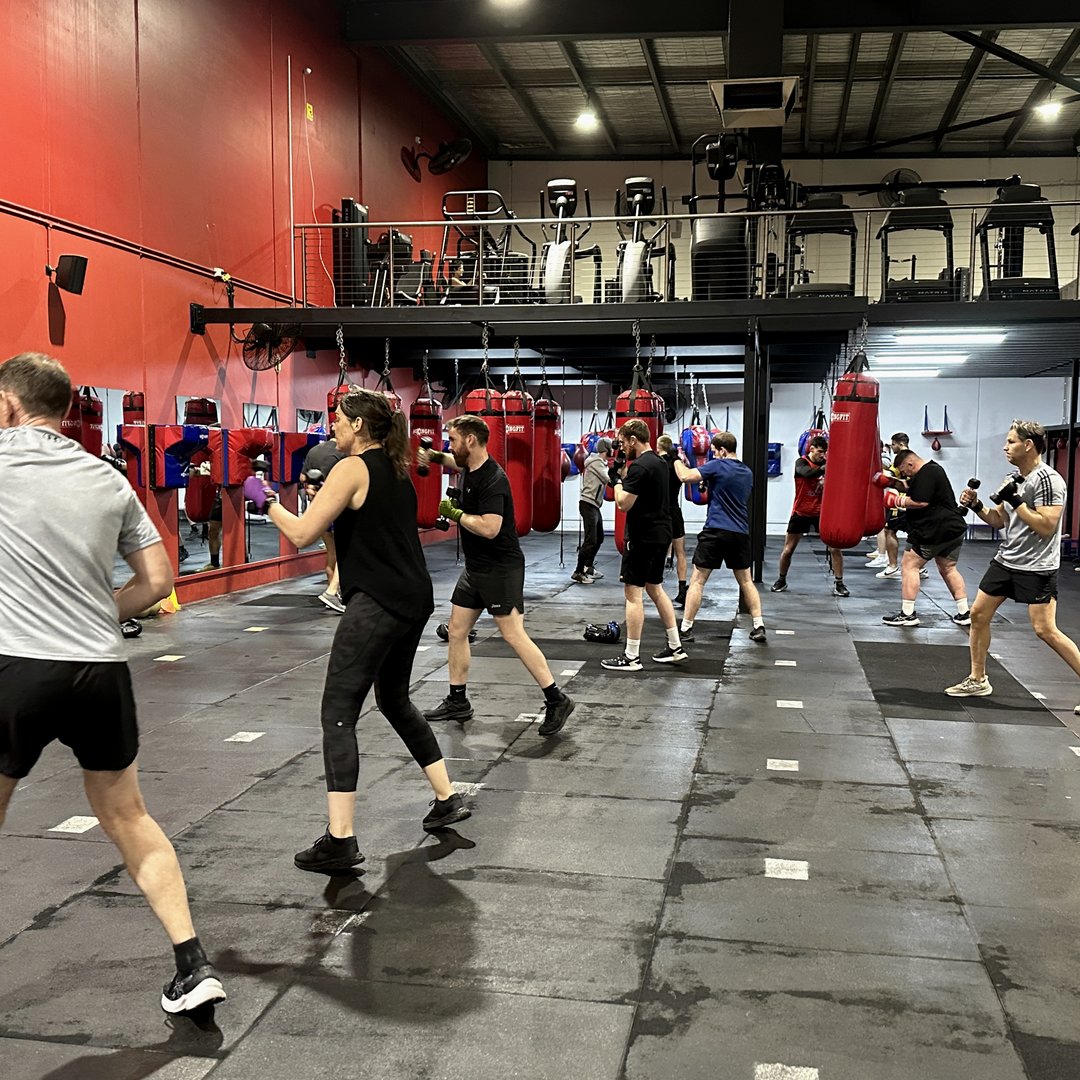 Boxing class shadow boxing in front of the bags